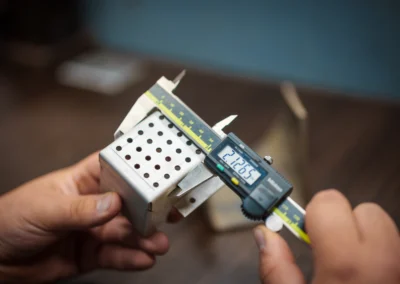 Digital caliper measuring a metal object held by a person's hands