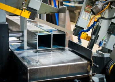 Industrial metal saw cutting through steel tubing.