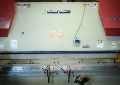 Industrial press brake machine in a workshop with warning labels