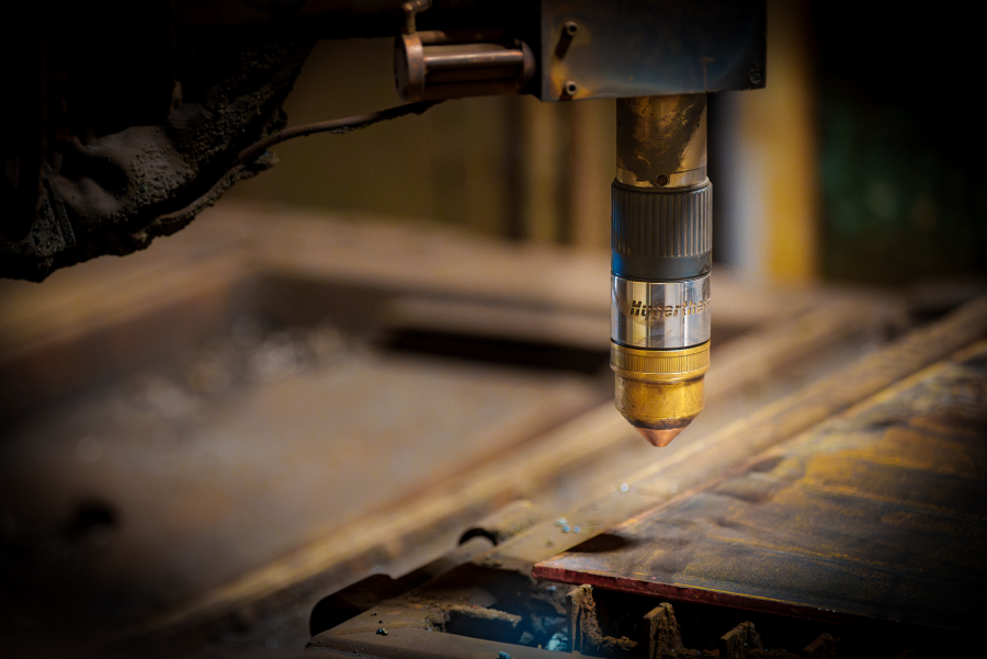 Close-up of a welding torch poised over a metal workpiece, showcasing intricate details of the nozzle and surrounding machinery. Close-up of a welding torch poised over a metal workpiece, showcasing intricate details of the nozzle and surrounding machinery.